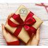 Obraz przedstawia prezent owinięty w złoty papier z czerwoną wstążką i kartką z napisem „Frohe Weihnachten”, co wskazuje na prezent bożonarodzeniowy.